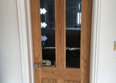 Wooden door in white frame. Dual glass panelling in door