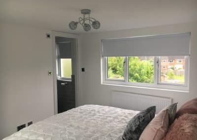 Finished loft conversion - triple window and white bedding with pink/grey cushions