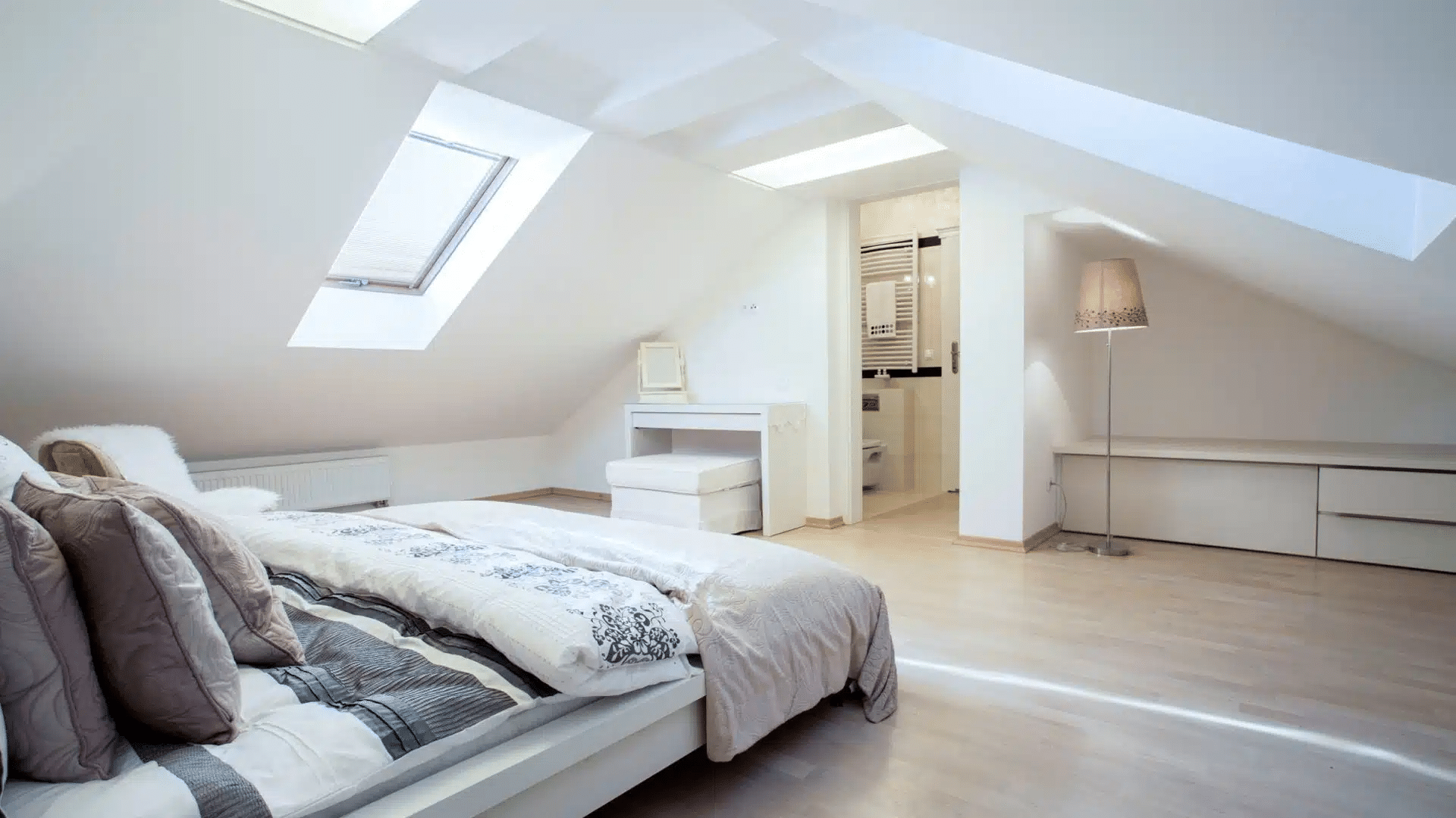Dormer conversion white room with bed made and bathroom